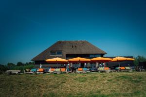 兹沃勒Buitenplaats de Luwte的一座配有橙色遮阳伞和桌椅的建筑