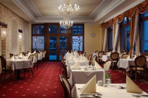 卡罗维发利洪堡公园及水疗酒店的餐厅配有白色的桌椅和吊灯