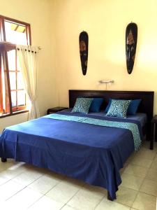 罗威那贾耶旅馆的一间卧室配有一张带蓝色床单的床和一扇窗户。