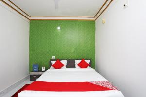 布巴内什瓦尔OYO Aradhya Residency的一间卧室配有一张带红色枕头的床和绿色的墙壁