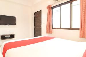 DehuNew Pune Residency的一间卧室设有一张床、一台电视和一个窗口。