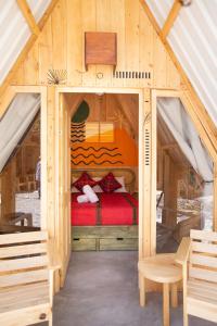 帕纳哈切尔Selina Atitlan的一张位于木屋内的床位,配有红色的床