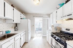 普里茅斯Beach Time的白色的厨房配有白色橱柜和炉灶。