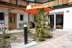 泰根塞Ferienwohnungen Rosenhof的庭院里带橙色遮阳伞的房子