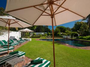 克尼斯纳克尼斯纳圣詹姆斯酒店的一组草坪椅和一把遮阳伞,位于游泳池旁