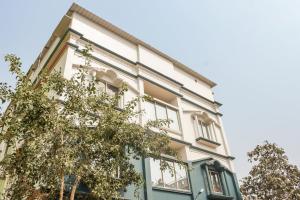 KhandagiriWelcome Inn Near DN Regalia的一座白色和蓝色的建筑,前面有树木