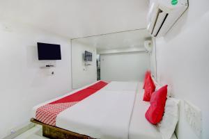 孟买OYO Hotel Blue Light Near Gateway Of India Mumbai的一间卧室配有一张带红色枕头的床和一台电视。