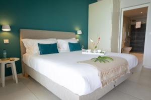 勒迪亚芒Eden Roc Villas的卧室配有白色大床和蓝色的墙壁