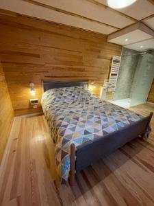 吕内维勒L'écolodge de Laeti的卧室配有一张床铺,位于带木墙的房间内