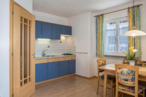 考那亚诺Valtlhof - Apt 2的厨房配有蓝色橱柜和餐桌