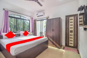 巴加Calangute Ocean Wave的一间卧室配有一张带红色枕头的床和一扇窗户