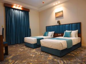 艾卜哈انباك للشقق المخدومه的两张位于酒店客房的床,配有蓝色窗帘