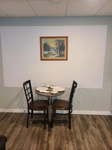 温尼伯Winnipeg Peace Home的一张桌子、两把椅子和墙上的一幅画
