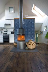 福里斯Driftwood Cottage, Findhorn Village的铺有木地板的厨房中间的壁炉