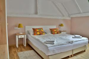 瓦乌布日赫新村旅馆的卧室配有一张带两张桌子的大型白色床