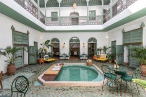 马拉喀什Riad Agathe & Spa的大型客房内的室内游泳池,配有桌椅