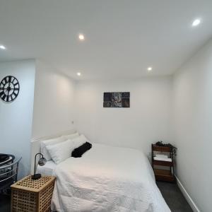 伦敦Maple House - Inviting 1-Bed Apartment in London的白色的卧室配有一张床和墙上的时钟