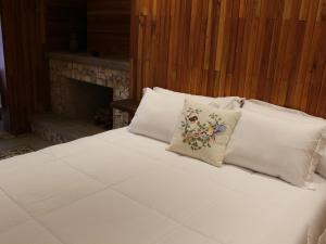 巴纳纳尔Fazenda Capuava的一张配有白色床单和枕头的床铺,配有壁炉