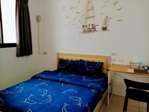 礁溪渔海民宿的一间卧室配有一张带蓝色床单的床和一张书桌。