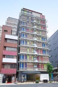 大阪Sotetsu Grand Fresa Osaka-Namba的一座高大的公寓楼,设有色彩缤纷的窗户
