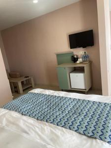 NatakhtariRoyal Green Hotel的卧室配有一张床,墙上配有电视。