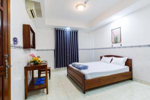 Dĩ AnHoa Cúc Phương Hotel Dĩ An - Bình Dương的一间卧室配有一张床、一张桌子和一个窗户。