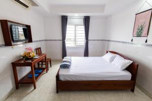 Dĩ AnHoa Cúc Phương Hotel Dĩ An - Bình Dương的一间卧室配有一张床、一张桌子和一个窗户。