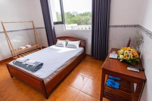 Dĩ AnHoa Cúc Phương Hotel Dĩ An - Bình Dương的一间卧室配有一张床和一张鲜花桌子