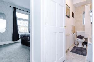 布雷得佛65 Inch TV & Luxurious 2 Bedroom Suite for Your Ultimate Getaway的白色的浴室设有卫生间和窗户。