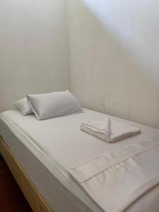 利比里亚Puente Real Hostel的一张带白色床单和枕头的床