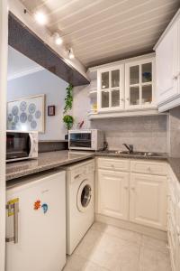 卡帕里卡海岸JOIVY Vibrant flat with balcony的厨房配有白色橱柜、洗衣机和烘干机
