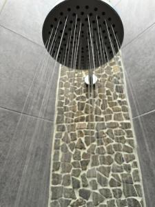 乌鲁瓦图Asri Villas Bingin的配有石地板和淋浴头的淋浴