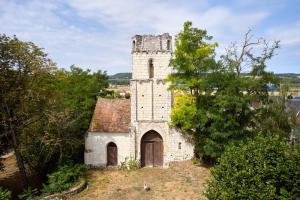 IngrandesGlamping Loire Valley的一座古老的石头建筑,在田野上建有塔
