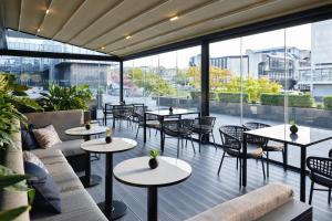 萨格勒布Maistra City Vibes Hotel International的餐厅设有桌椅和大窗户。