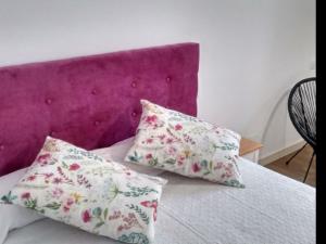 BosquemadoApartment 2 Bedrooms 8951的床上的2个枕头和紫色床头板