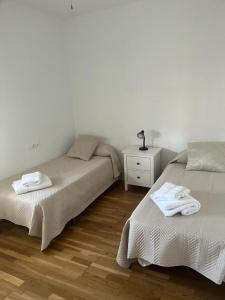 埃希哈ático con terraza- solarium的一间卧室配有两张床和一个带毛巾的梳妆台。