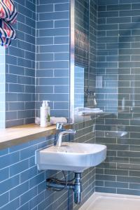 Great WilbrahamThe Carpenters Arms的蓝色瓷砖浴室设有水槽和镜子