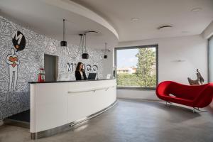 博洛尼亚Mitico Hotel & Natural Spa的坐在厨房柜台的红色椅子上的女人
