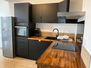 AndanceAppartement neuf avec garage的厨房配有黑色橱柜和木制台面