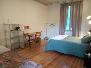 洛特河畔卡斯泰尔莫龙Lulu的一间卧室设有两张床、一张桌子和一个窗口