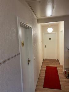 Otterbach亚历克斯酒廊运动吧吸烟休息室酒店的一条有红色地毯和白色门的走廊