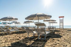 利尼亚诺萨比亚多罗雅典娜酒店 的海滩上的一组椅子和遮阳伞