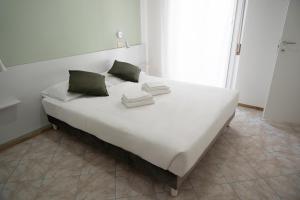 里米尼Hotel The Sea的一张带两个绿色枕头的大型白色床