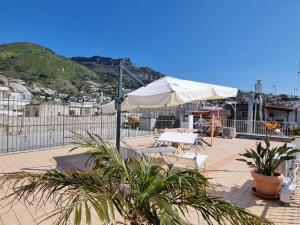 伊斯基亚Bella D'Estate - 10 minutes from the beach的一个带遮阳伞和两把椅子及植物的庭院