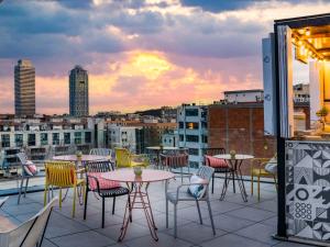 巴塞罗那巴塞罗那市博加特尔宜必思尚品酒店的日落时分带桌椅的屋顶露台