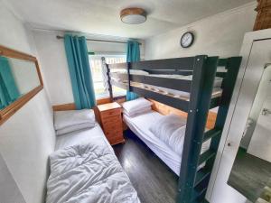 斯旺西Caswell Beach Chalet 70 located in Gower Peninsula的一间卧室设有两张双层床和一扇窗户。