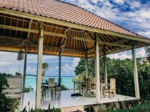 蓝梦岛Lebaoh Nusa Cottage的一个带桌椅的凉亭和大海