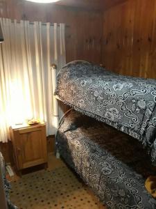 波特雷里约斯Cabaña Familiar El Refugio的一间卧室配有一张带枕头和桌子的床