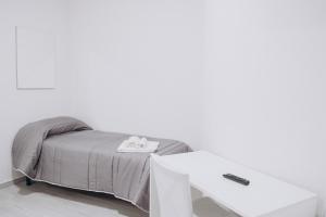 TrevicoPrestige的白色墙壁旁边的一张带白色桌子的床