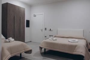 TrevicoPrestige的一间白色卧室,配有两张床和一个衣柜